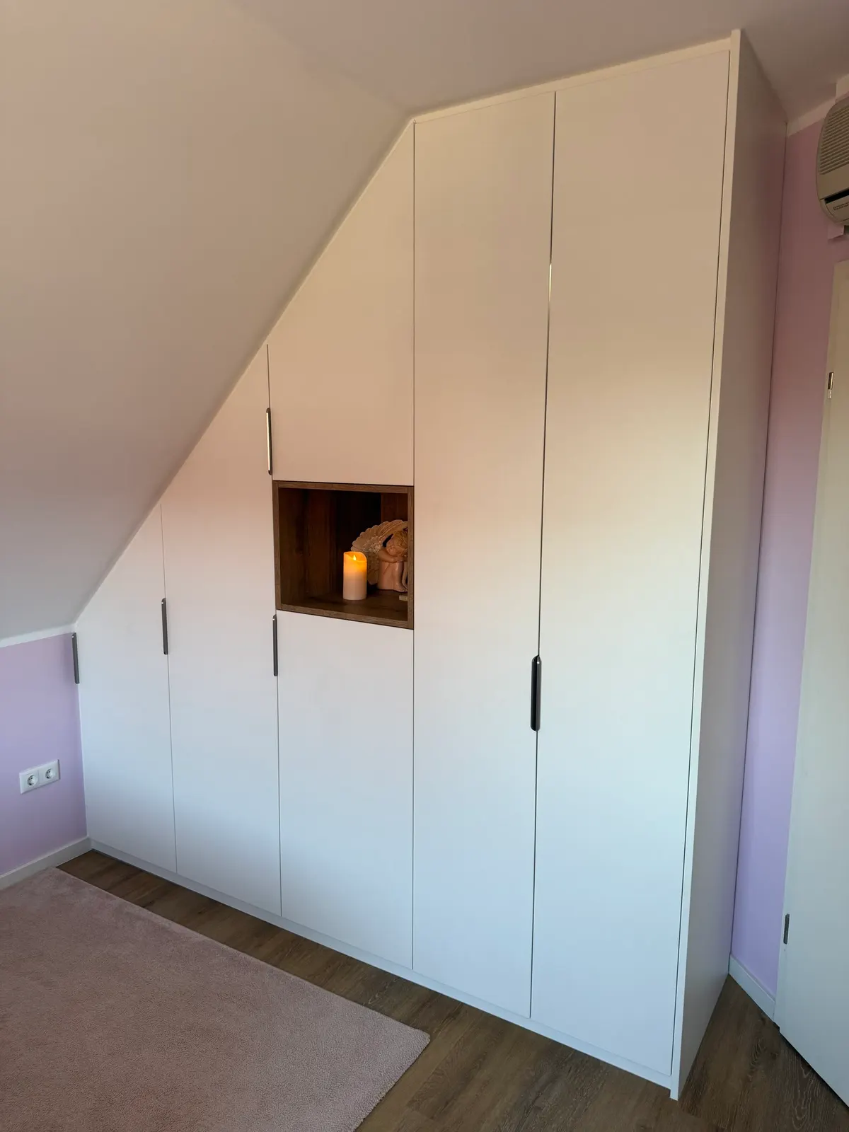 Weißer Einbauschrank in der Dachschräge mit offener Nische aus Holz